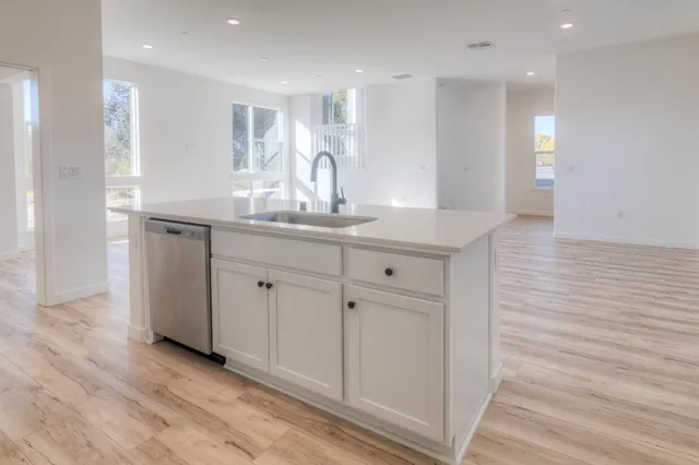 a kitchen with white cabinets a sink and wooden floor