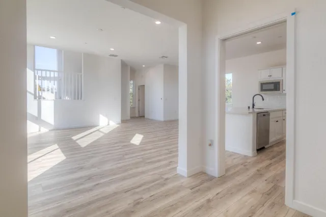 a view of a hallway with wooden floor and a bathroom