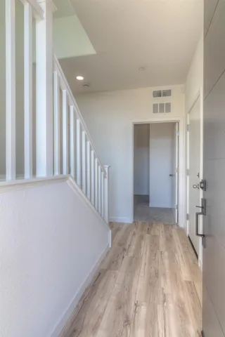 a view of hallway with a front door and wooden floor