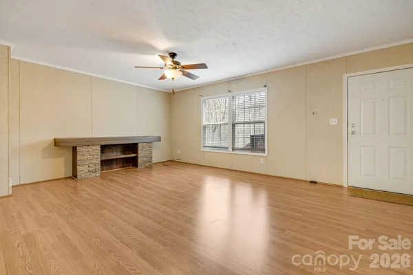 an empty room with wooden floor fireplace and windows