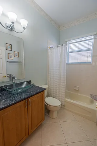 a bathroom with a granite countertop sink a toilet a mirror and shower