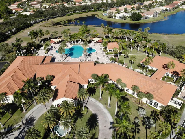 a view of swimming pool that has lawn chairs with plants and palm trees