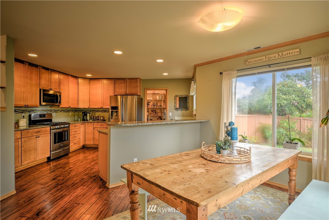 20398 Springbrook Road Southeast Monroe, WA 98272 - Photo 5 of 39 a kitchen with stainless steel appliances granite countertop a stove a refrigerator a sink dishwasher with a dining table and chairs with wooden floor