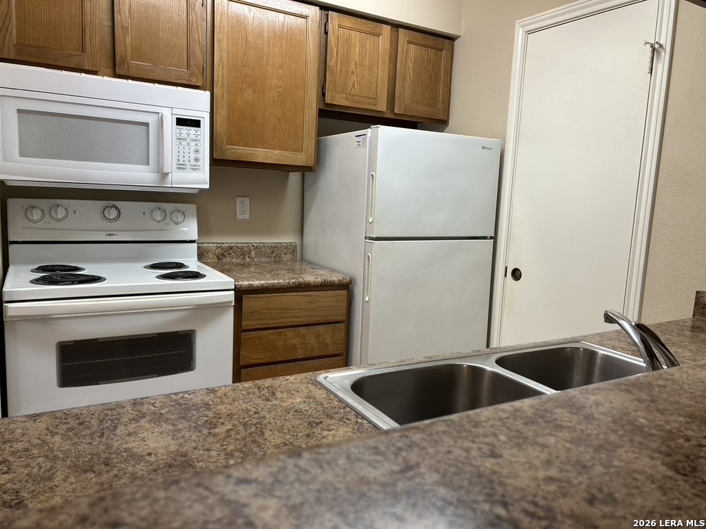 13018 Heimer Road, Unit 710 San Antonio, TX 78216 - Photo 12 of 27 a kitchen with granite countertop a sink and a refrigerator