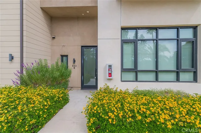 a front view of a house with a large window and flower plants
