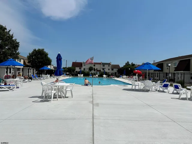 a view of the patio with dining table and chairs under an umbrella
