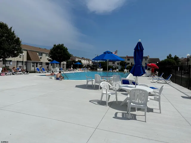 a view of the patio with dining table and chairs under an umbrella