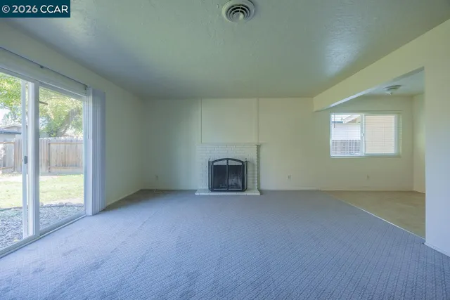 an empty room with fireplace and a floor to ceiling window