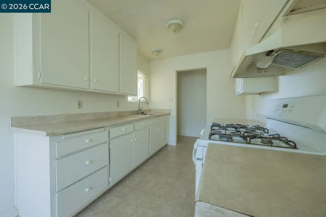 a kitchen with cabinets stove and white countertops