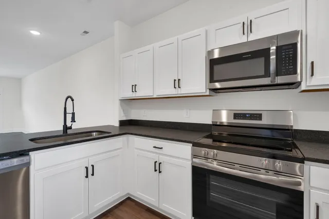 a kitchen with stainless steel appliances granite countertop white cabinets and black stove top