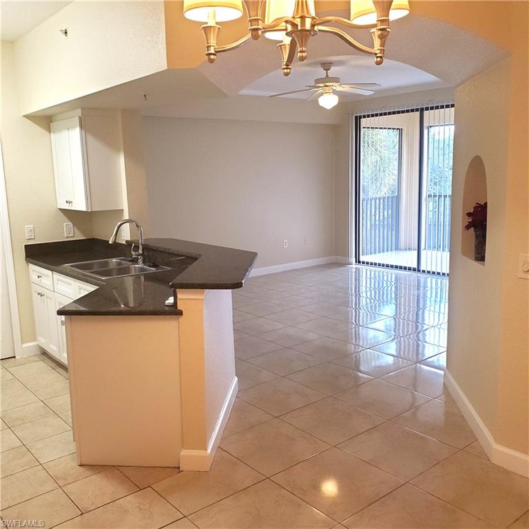 12980 Positano Circle, Unit 207 Naples, FL 34105 - Photo 3 of 23 a kitchen with granite countertop a sink a stove a refrigerator and cabinets