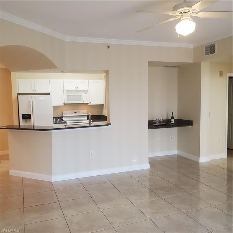 12980 Positano Circle, Unit 207 Naples, FL 34105 - Photo 4 of 23 a kitchen with kitchen island granite countertop a refrigerator a sink and a stove