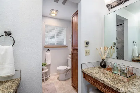 a bathroom with a granite countertop sink a toilet and mirror