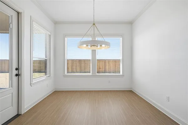 an empty room with wooden floor chandelier and window