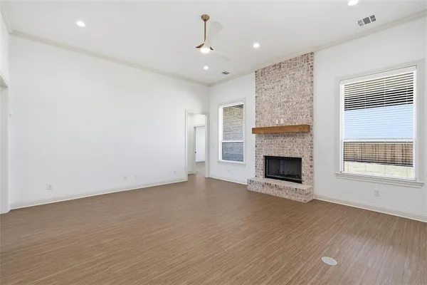 a view of an empty room with wooden floor fireplace and a window