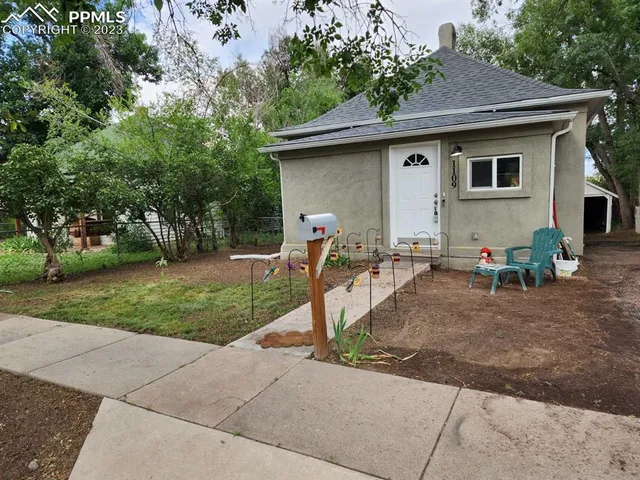 a front view of a house with garden and trees