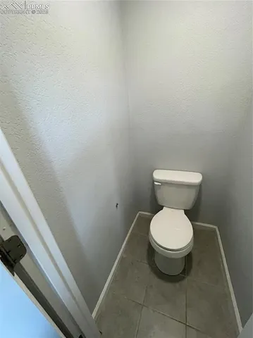 a white toilet sitting in a bathroom next to a white wall