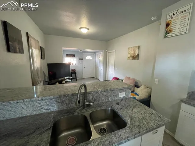 a kitchen with a sink a counter top space and a view of living room