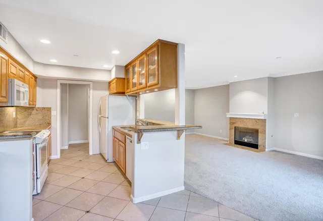a kitchen with granite countertop a refrigerator a stove and a sink with fireplace