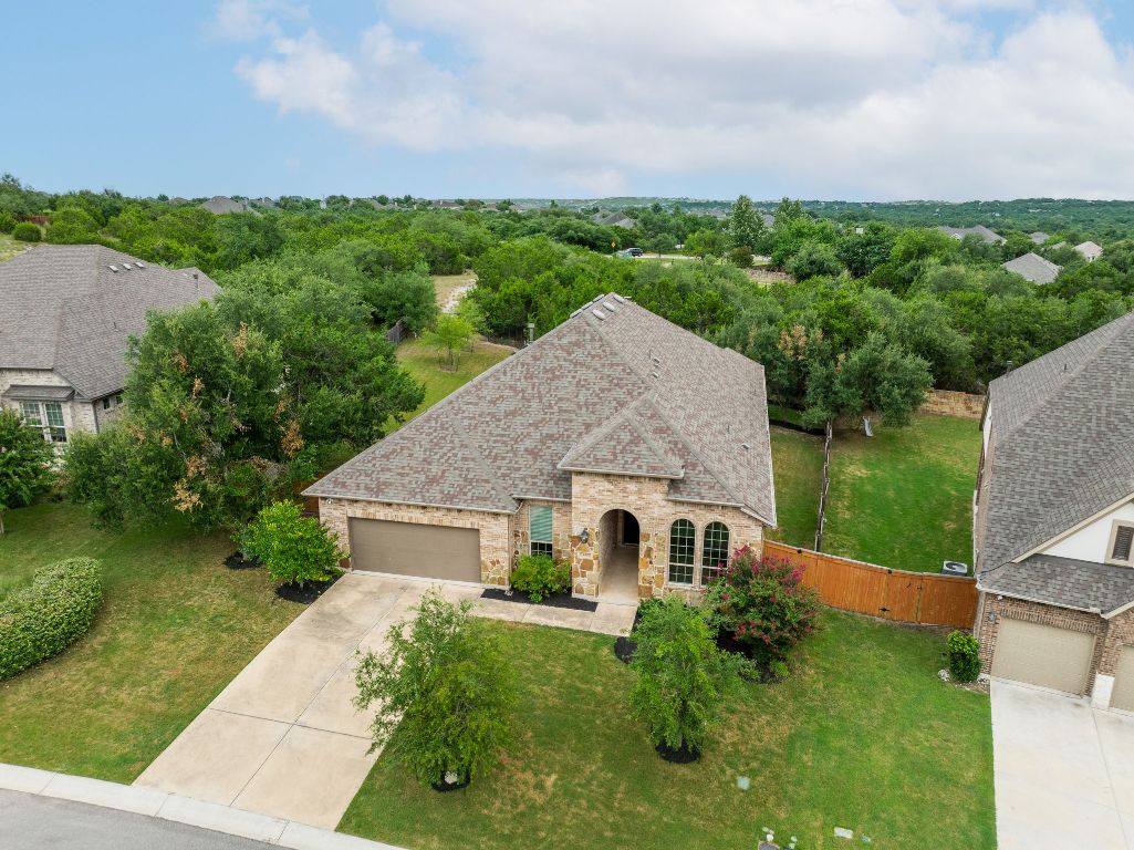 Front exterior featuring concrete driveway, a 3-car garage (right side is tandem), shingle roof, stone and brick exterior