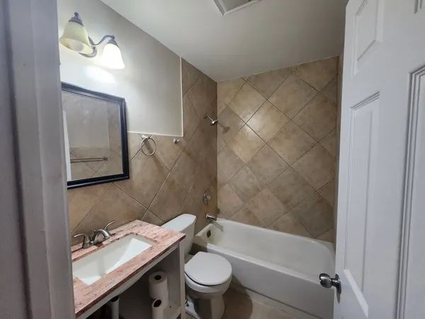 a bathroom with a granite countertop sink a toilet and shower