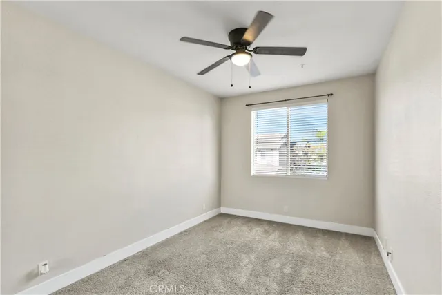 an empty room with a window and a fan