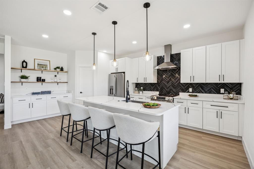 a kitchen with stainless steel appliances kitchen island a table chairs sink and cabinets