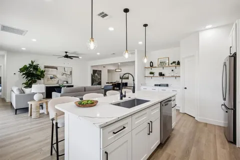 a kitchen with a sink a refrigerator and wooden floor