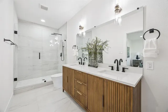 a bathroom with a sink double vanity granite tub shower and mirror