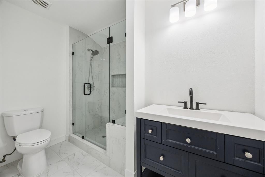 2516 Sunridge Road Carrollton, TX 75006 - Photo 22 of 39 a bathroom with a toilet a sink a mirror and shower