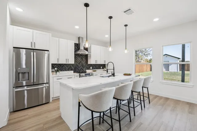 a kitchen with stainless steel appliances a dining table chairs and wooden floor