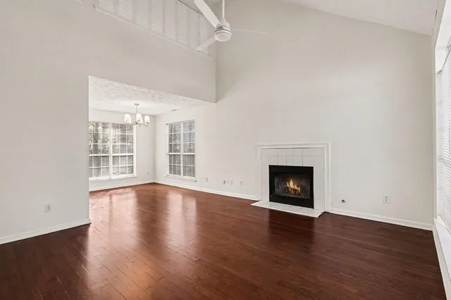 a view of an empty room with wooden floor fireplace and a window