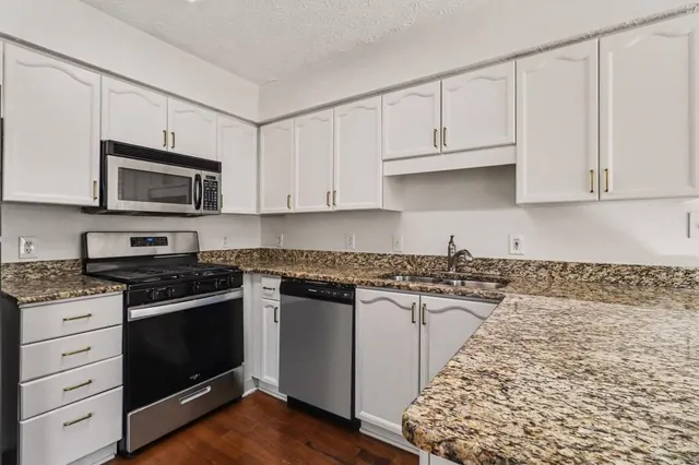 a kitchen with granite countertop white cabinets and stainless steel appliances