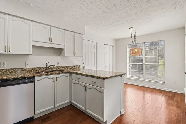 a kitchen with granite countertop white cabinets and a wooden floor