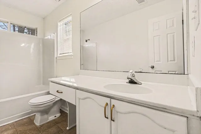 a bathroom with a granite countertop sink a toilet and a mirror