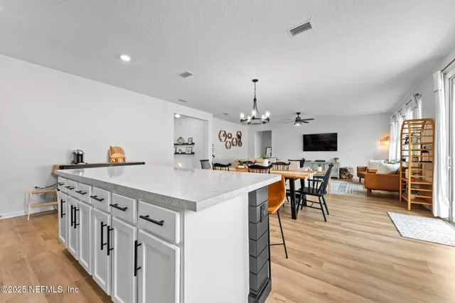 a kitchen with granite countertop a stove top oven a sink dishwasher and white cabinets with wooden floor