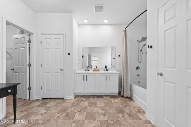 a bathroom with a double vanity sink a mirror a bathtub and shower