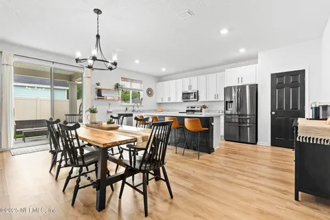 a kitchen with stainless steel appliances granite countertop a refrigerator a stove a sink a dining table and chairs with wooden floor