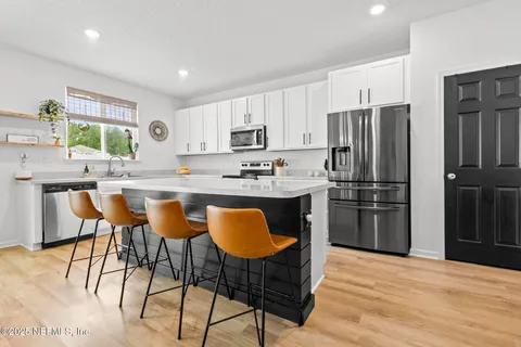 a kitchen with stainless steel appliances granite countertop a table chairs sink refrigerator and cabinets