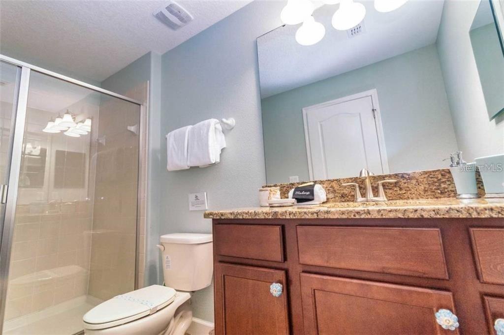 1427 Thunderbird Road Davenport, FL 33896 - Photo 21 of 52 a bathroom with a granite countertop sink a toilet a mirror and shower