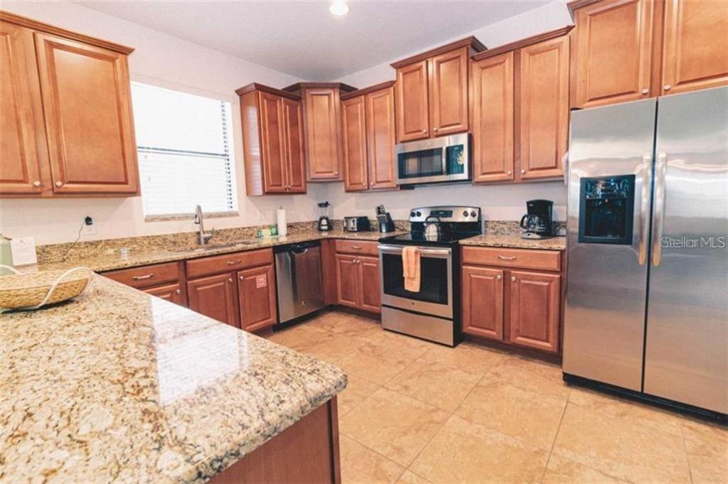 1427 Thunderbird Road Davenport, FL 33896 - Photo 8 of 52 a kitchen with stainless steel appliances granite countertop a sink stove and refrigerator