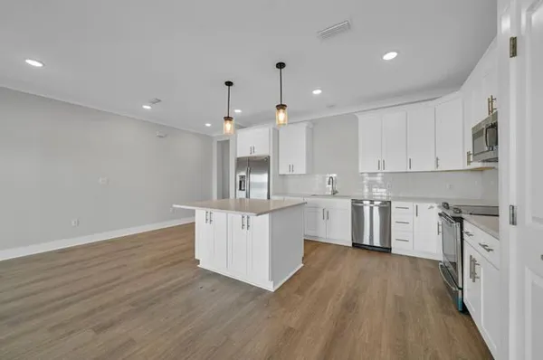 a large kitchen with cabinets wooden floor and stainless steel appliances