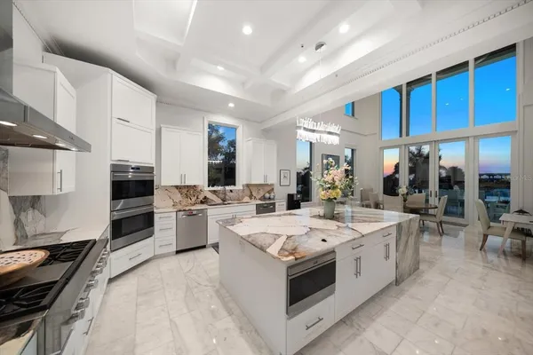 a large kitchen with stainless steel appliances kitchen island granite countertop a large stove a sink dishwasher and white cabinets with wooden floor