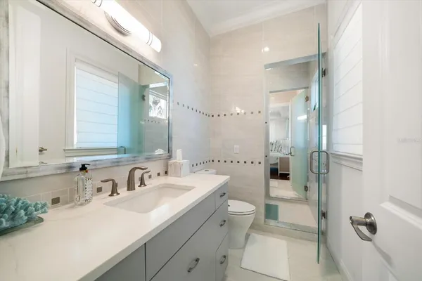 a bathroom with a double vanity sink toilet mirror and shower
