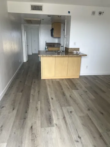a view of a kitchen with kitchen island a sink wooden floor and a counter top space
