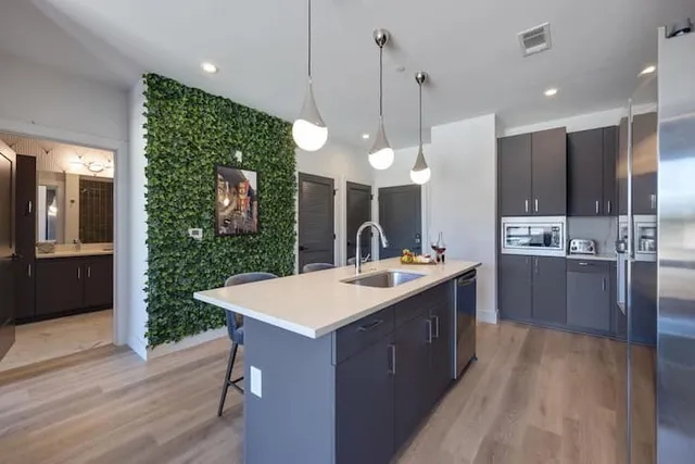 a large kitchen with kitchen island a sink stainless steel appliances and a chandelier