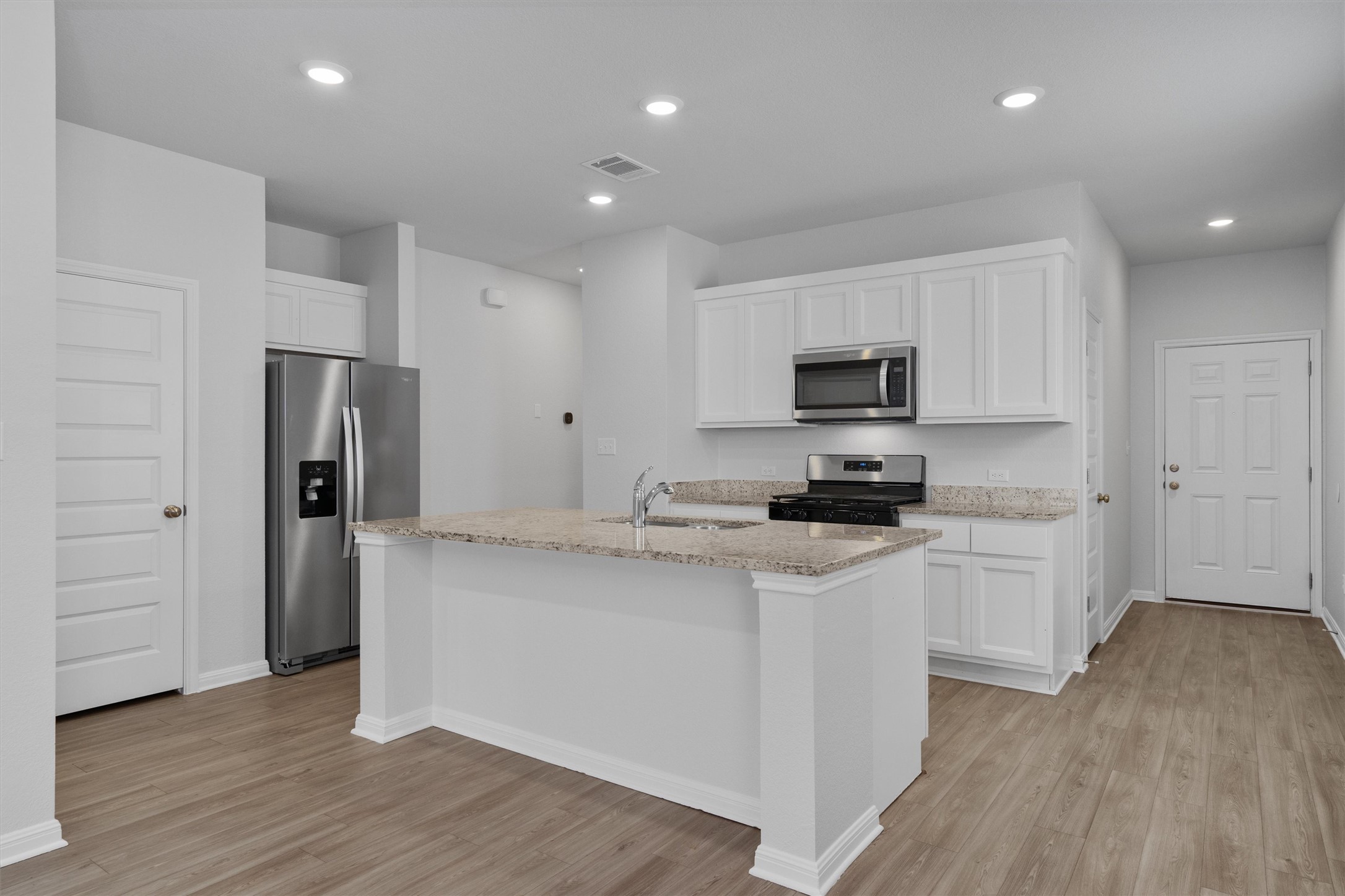 10613 Ridan Way Buda, TX 78610 - Photo 4 of 32 a kitchen with a sink a microwave a refrigerator and cabinets