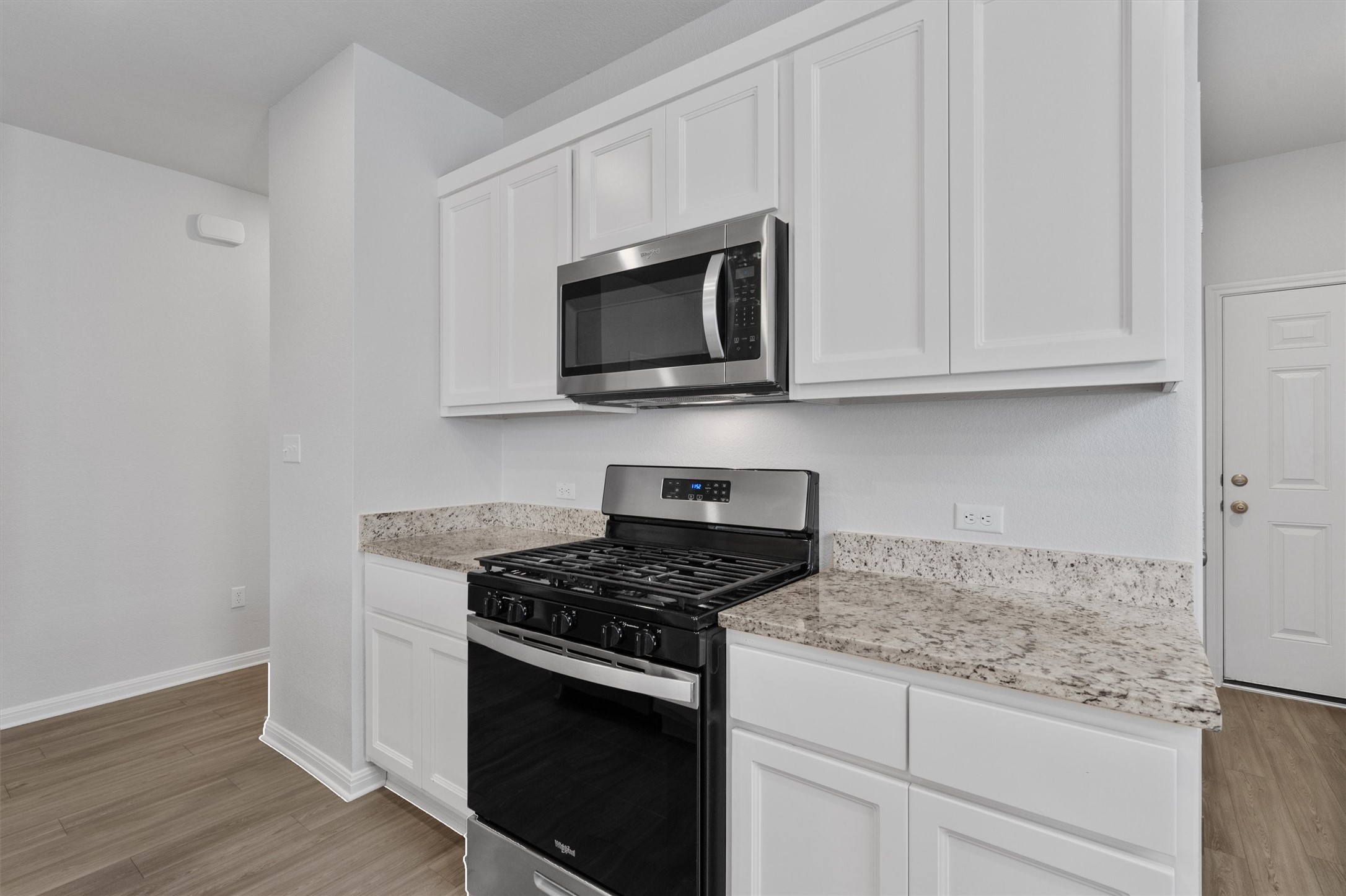 10613 Ridan Way Buda, TX 78610 - Photo 7 of 32 a kitchen with granite countertop white cabinets and black appliances