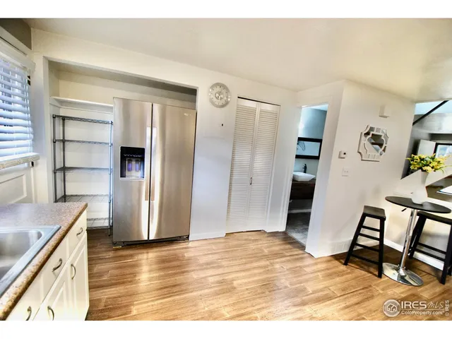 a kitchen with stainless steel appliances kitchen island granite countertop a sink dishwasher stove and white cabinets with wooden floor