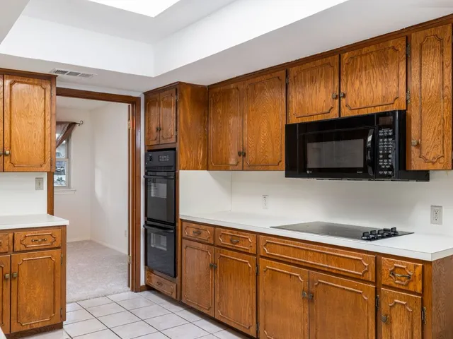 a kitchen with stainless steel appliances granite countertop a refrigerator a stove and a sink with wooden cabinets
